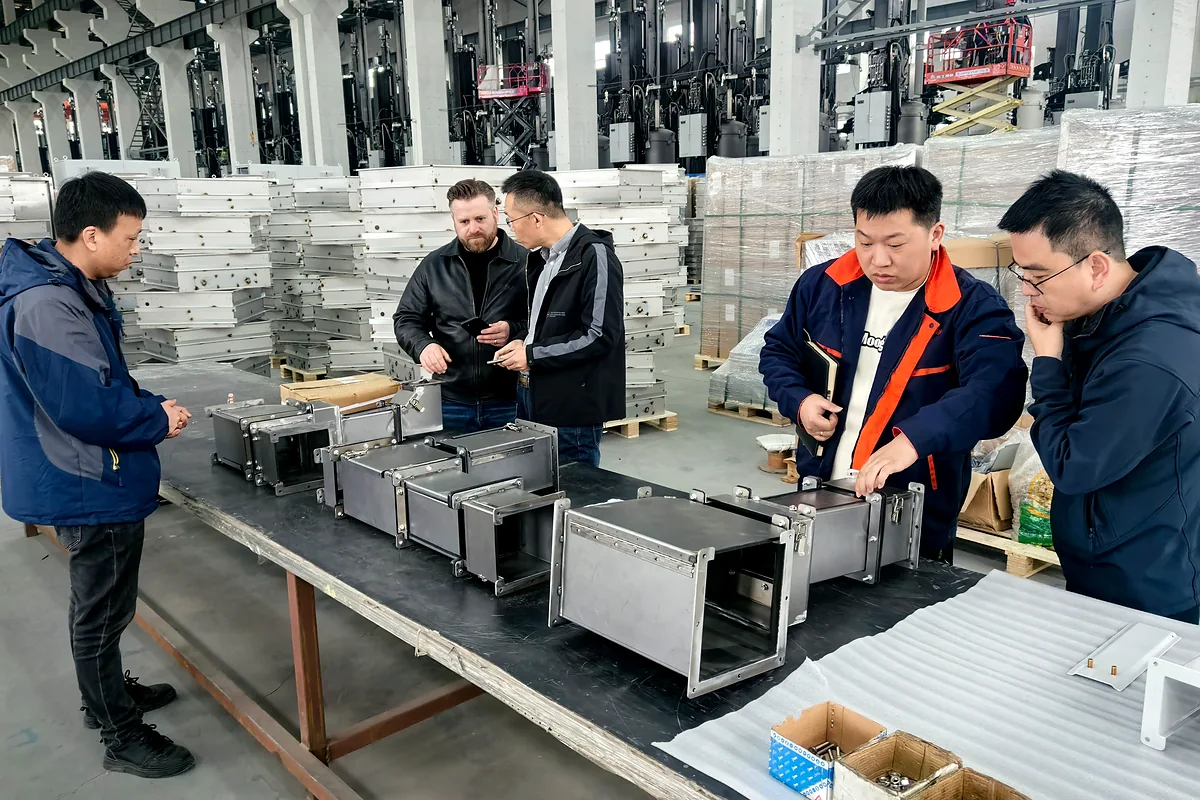 Des visiteurs examinent des composants d'enceinte fabriqués lors d'une visite d'usine.