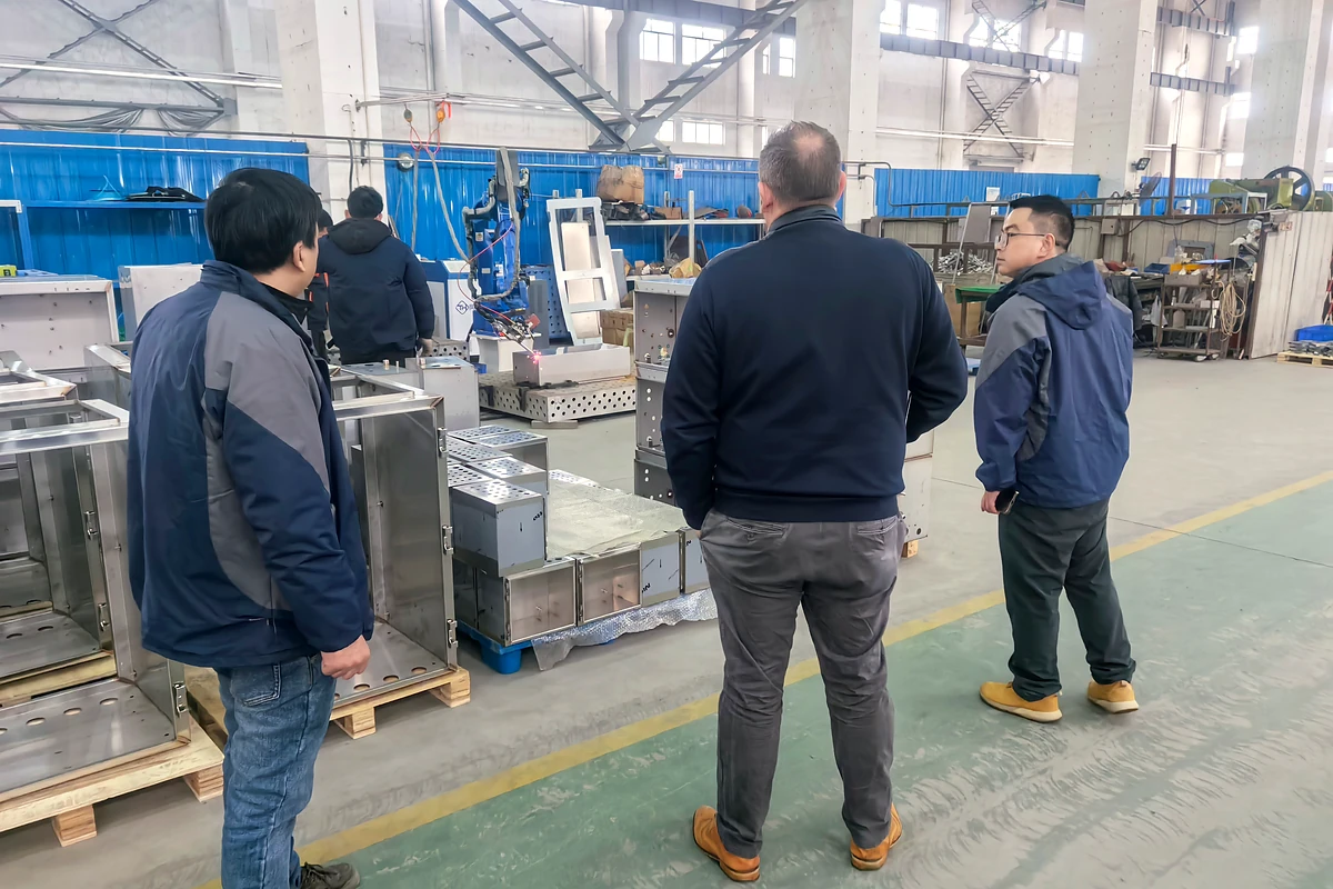 Visite de l'usine : des visiteurs observent la production d'enceintes.