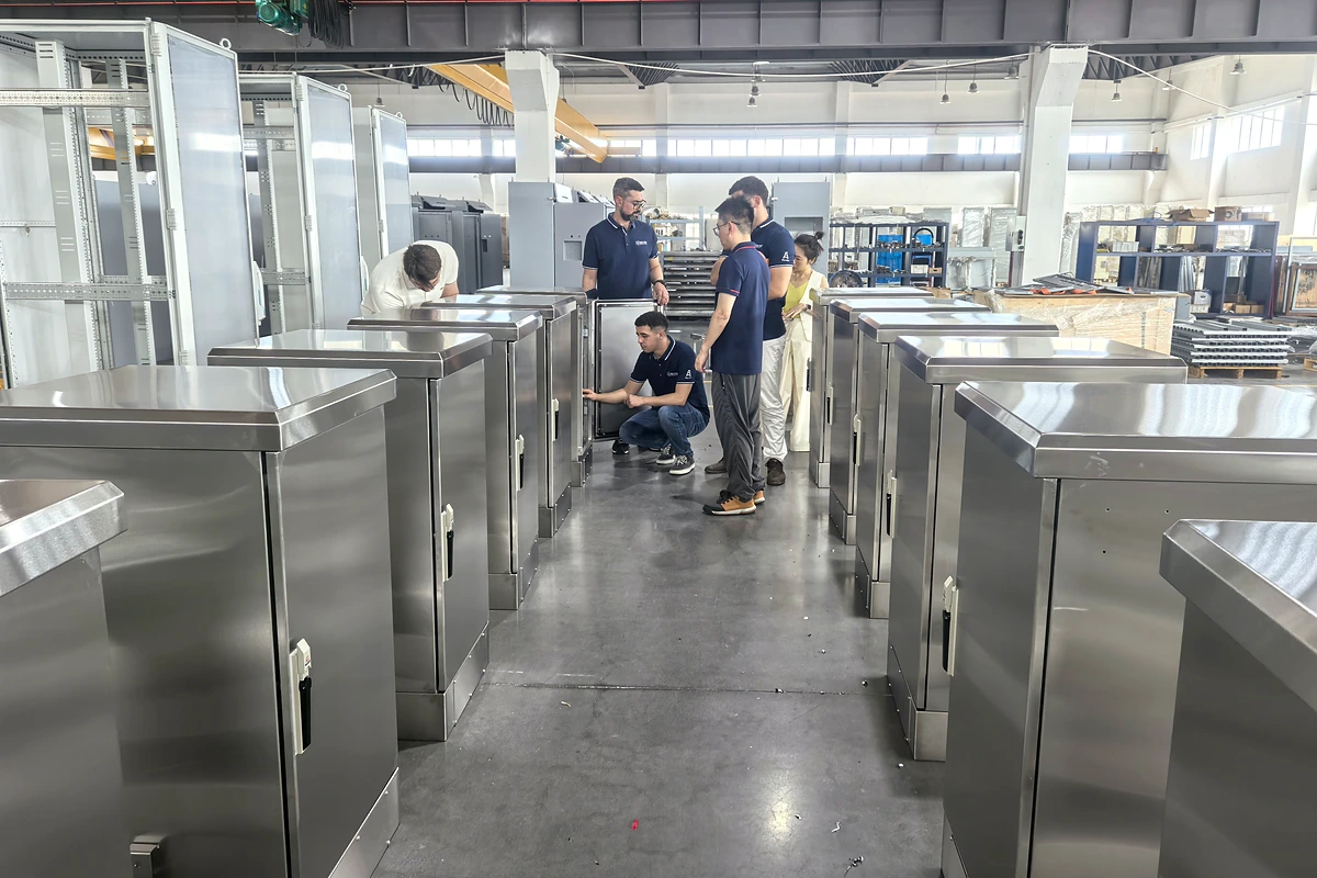 Des visiteurs examinent les boîtiers en acier inoxydable sur le plancher de l'usine