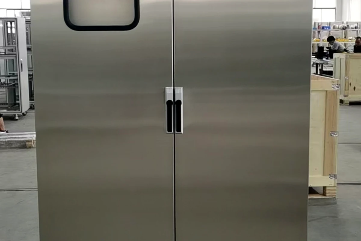 Kabinet listrik tinggi berbahan stainless steel yang berdiri di lantai.