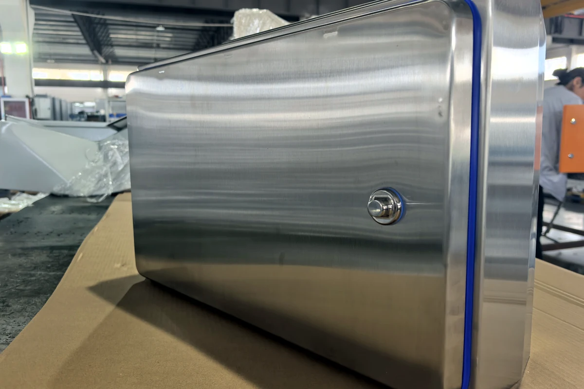 Kotak pelindung dinding berbahan stainless steel dengan bentuk bulat dan segel pintu berwarna biru.