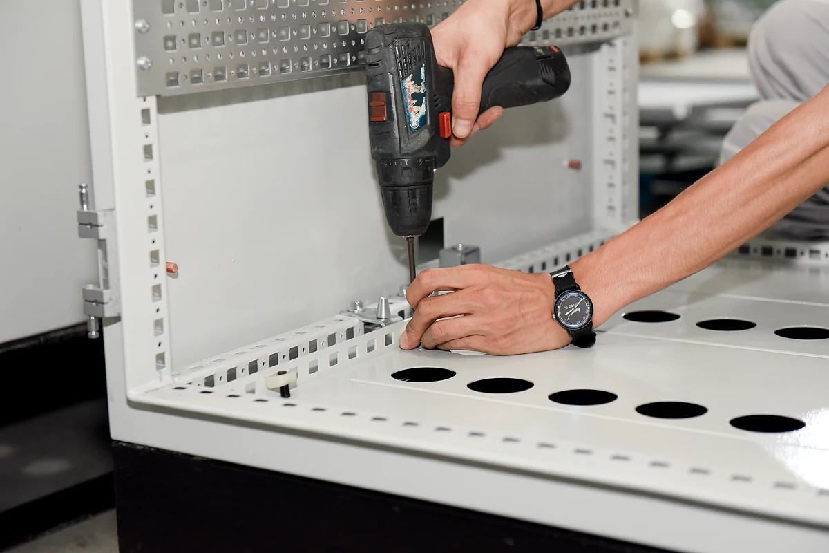 Technician assembling internal hardware in an electrical cabinet