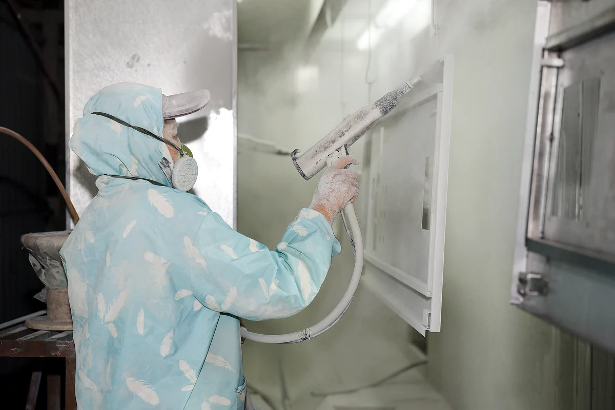 Worker powder coating an electrical enclosure panel